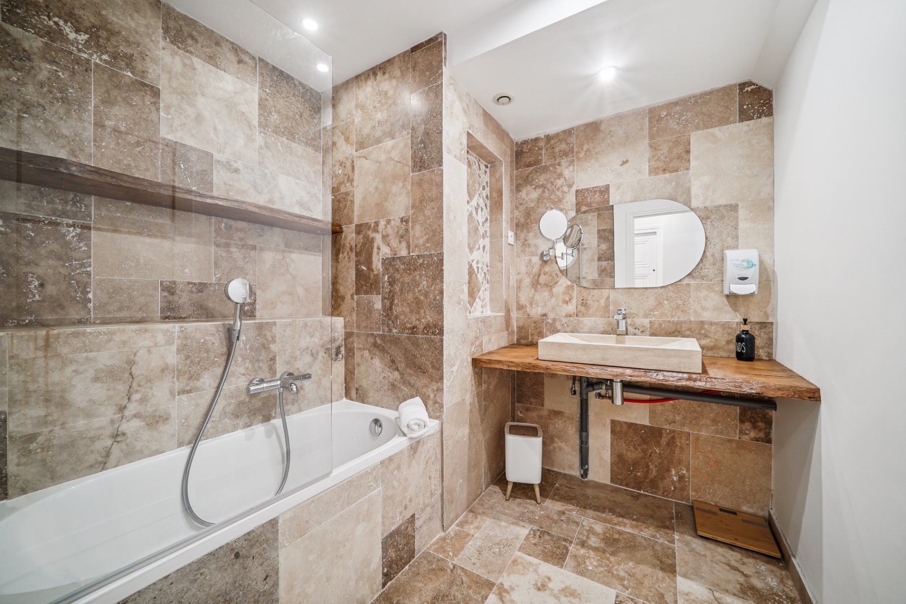 Salle de bain en travertin avec baignoire et vasque en pierre