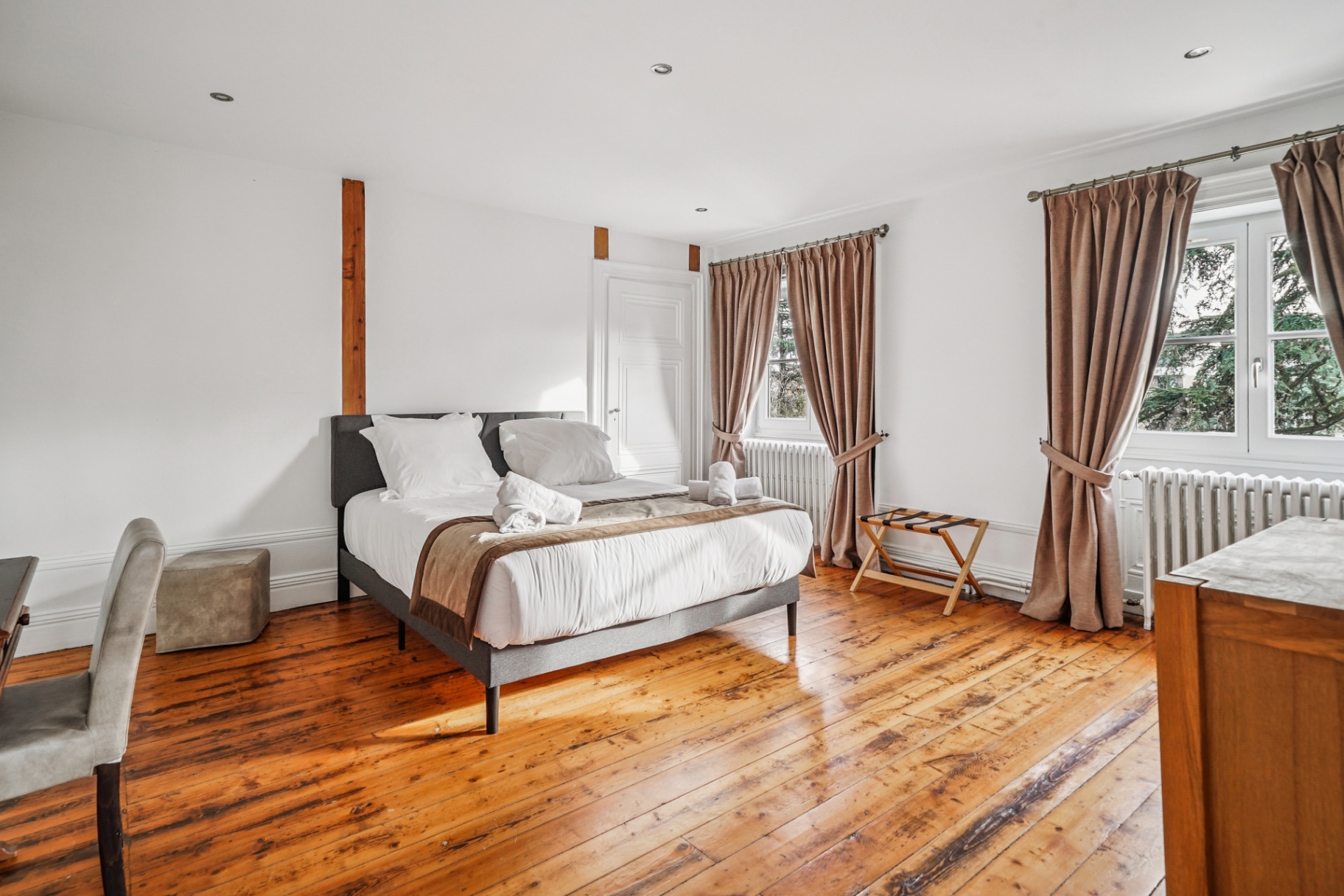 Chambre épurée avec parquet patiné et lit gris