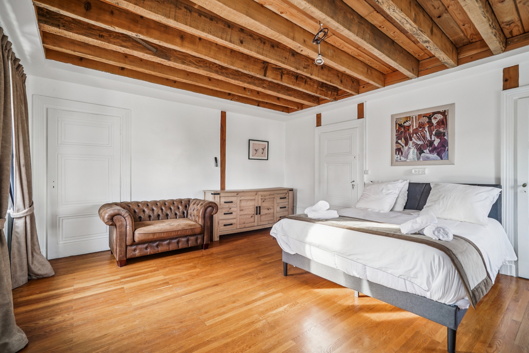 Chambre spacieuse, fauteuil Chesterfield et poutres en bois